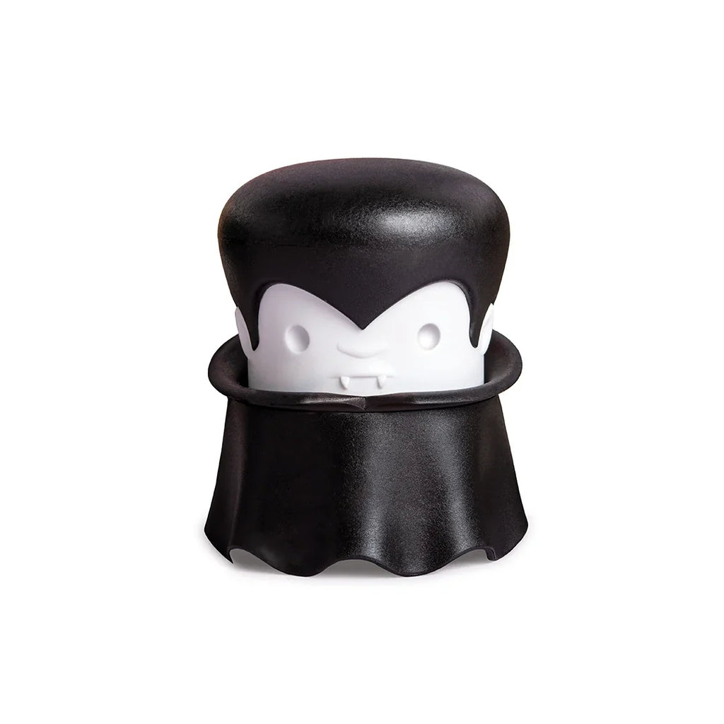 A cartoon vampire with a cape and fangs holds an OTOTO Gracula garlic crusher.